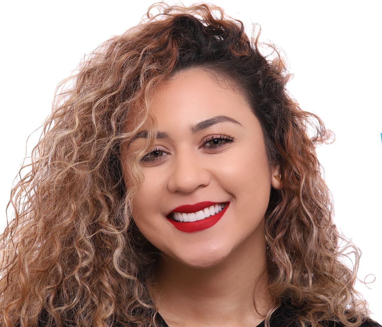 A woman with curly hair and red lipstick smiles for the camera