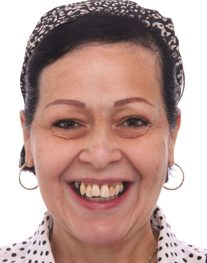 A woman wearing a headband and earrings smiles for the camera