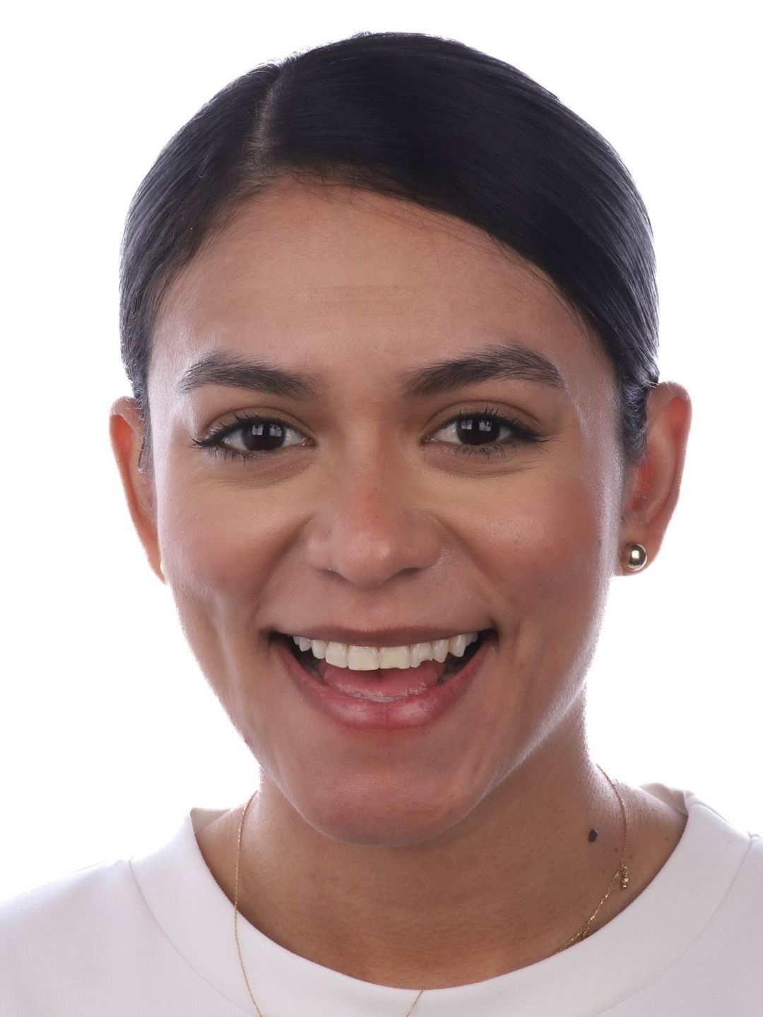 A woman wearing a white shirt and earrings smiles for the camera