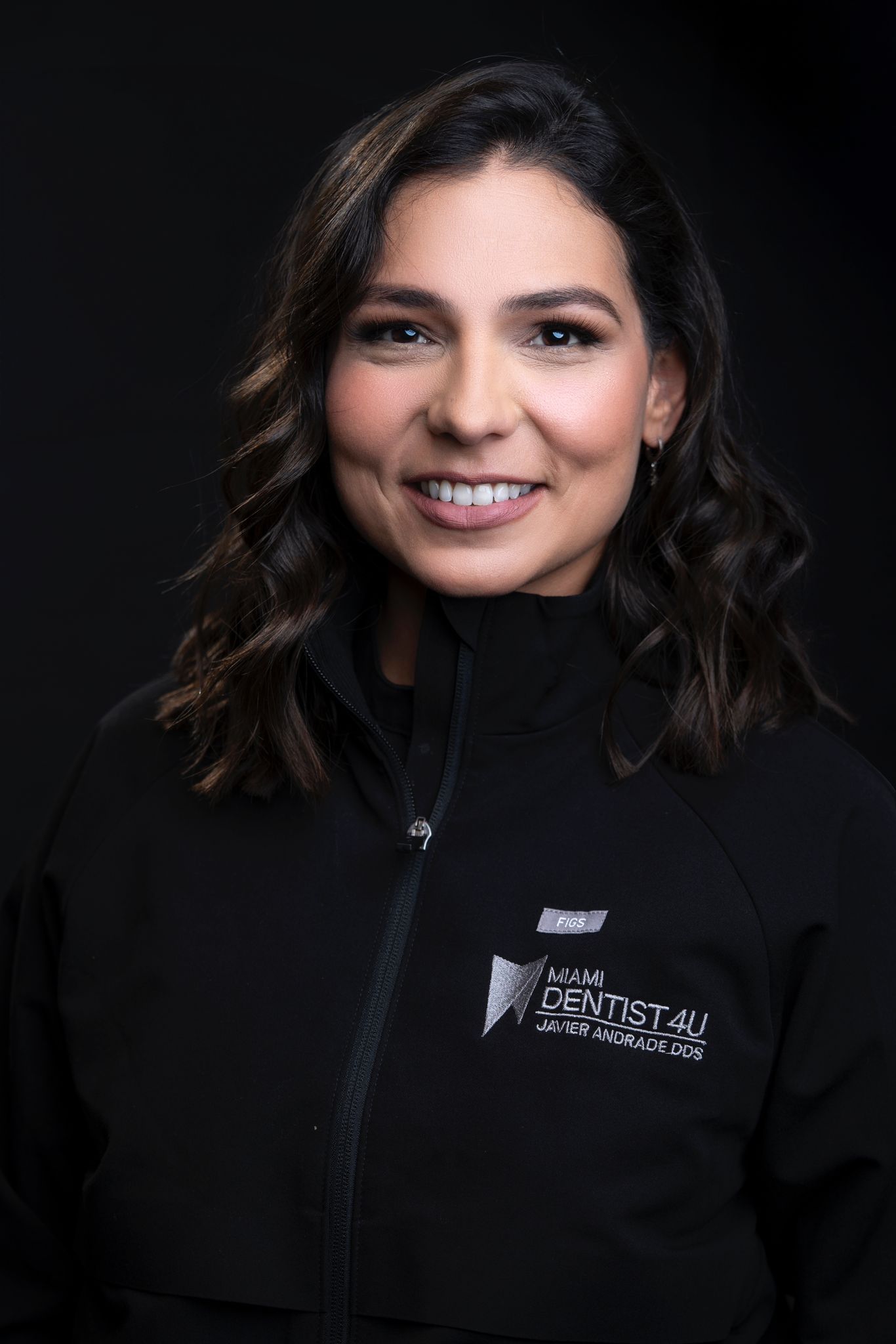 A woman is wearing a black jacket and smiling for the camera.