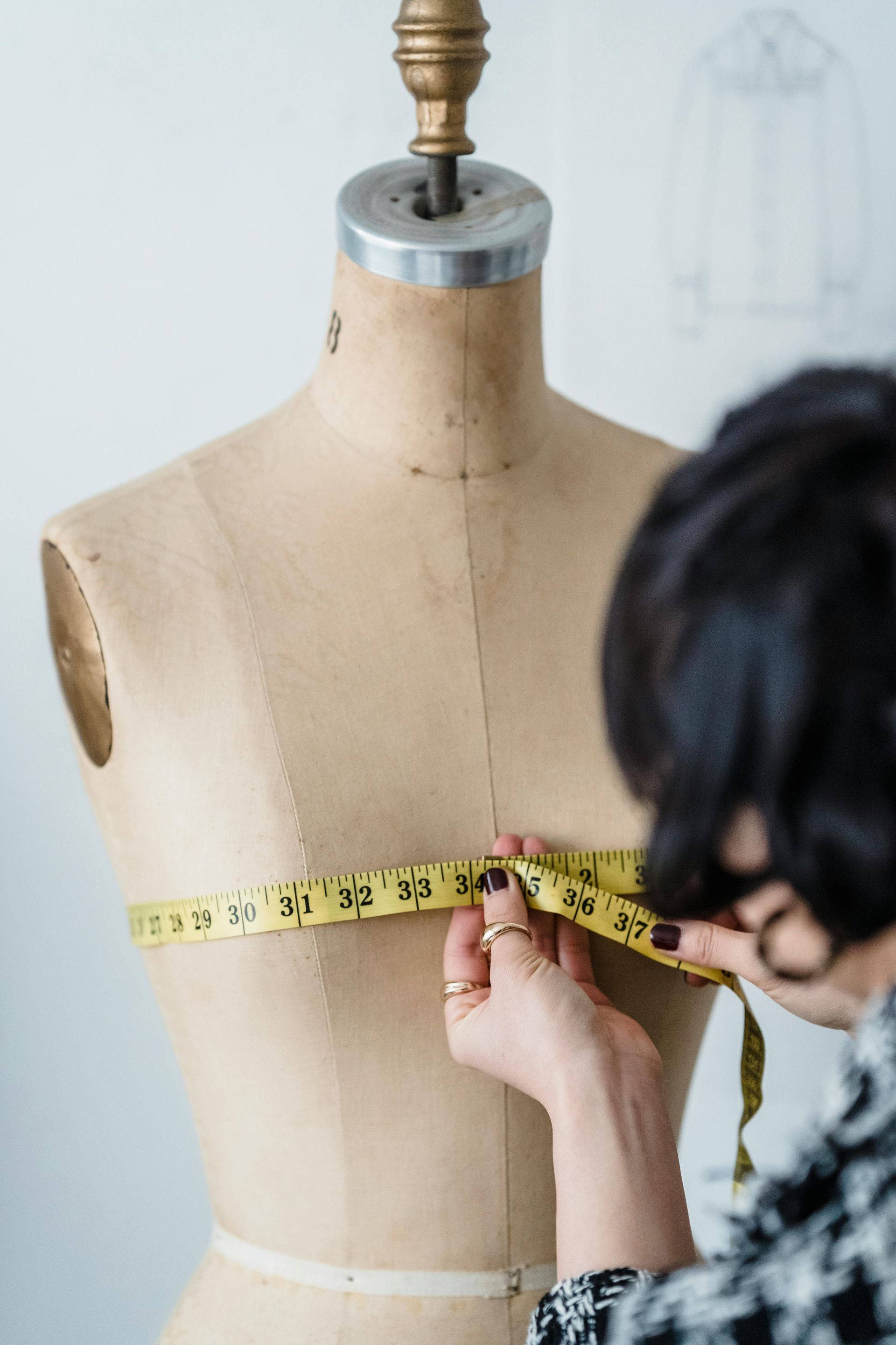A woman is measuring a mannequin 's chest with a tape measure.