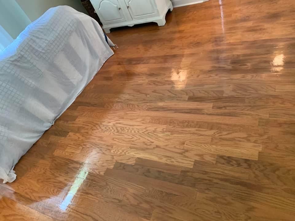 Wooden floor with light shining, a couch with a white blanket, and a white cabinet.