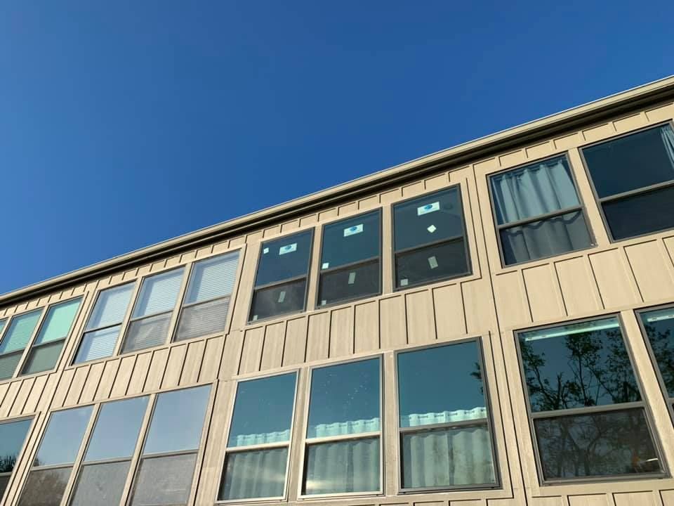 Tan building with multiple windows against a clear blue sky.