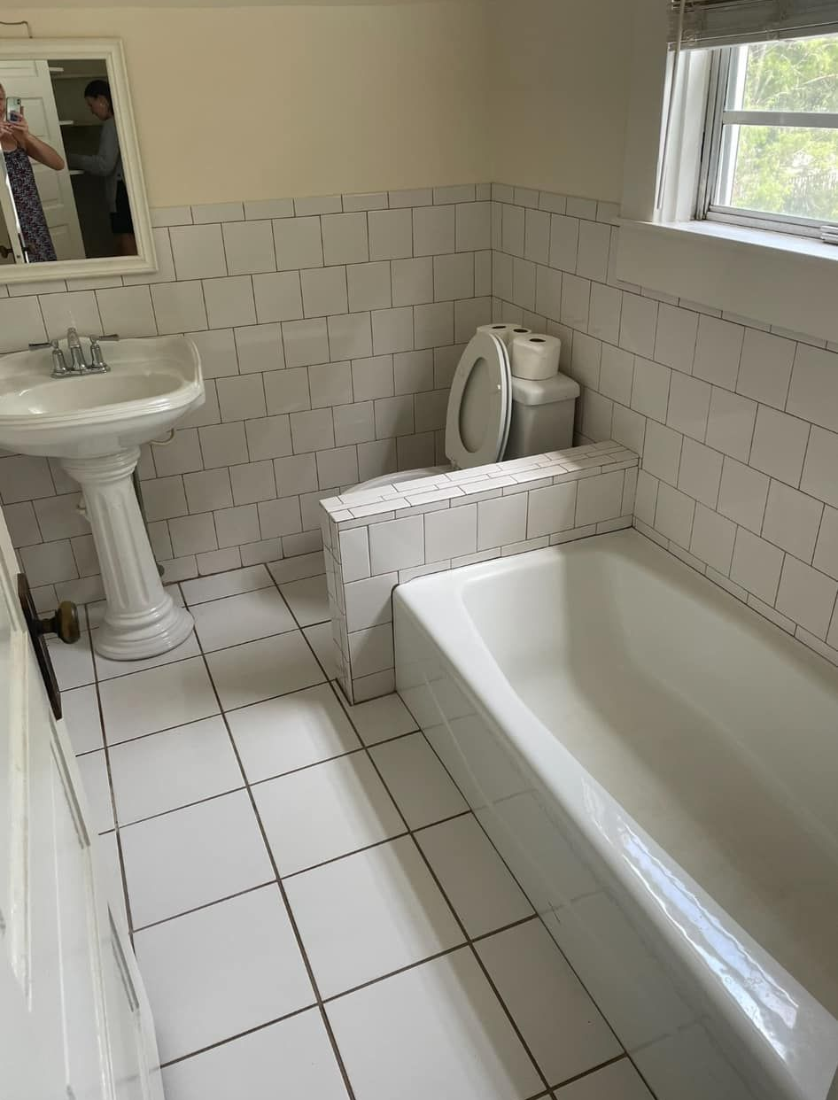 Bathroom with a white pedestal sink, bathtub, and tiled walls and floor.