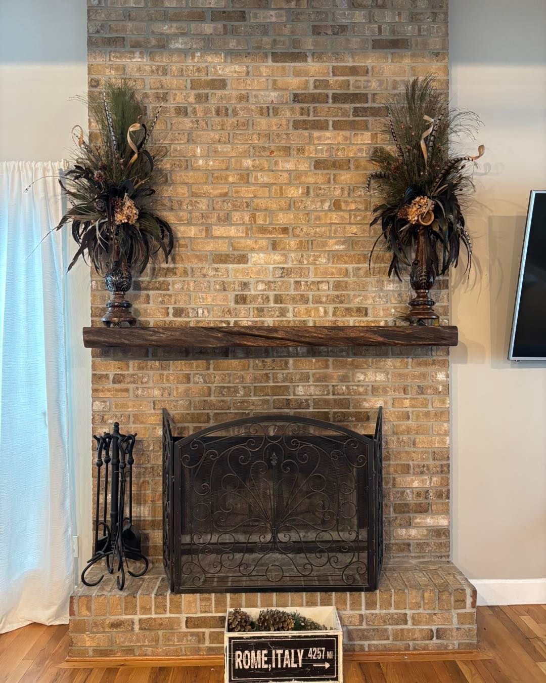 Brick fireplace with wooden mantel, decorative urns, and metal fire screen.