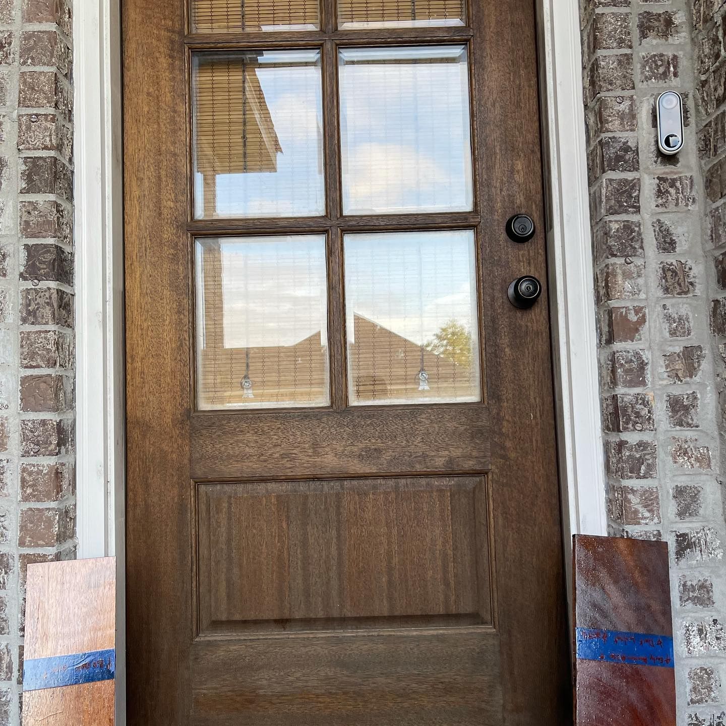 Brown wooden door with glass panels, brick wall, and blue stripe accents.