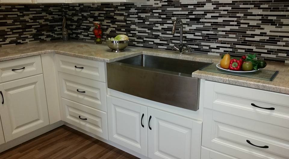 A kitchen with white cabinets and a stainless steel sink.