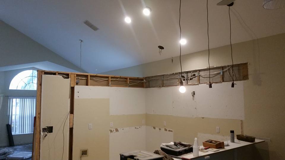 A kitchen under construction with a lot of lights hanging from the ceiling.