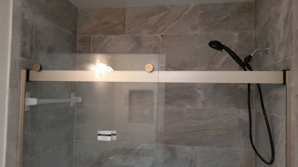 A shower with a sliding glass door and a shower head.