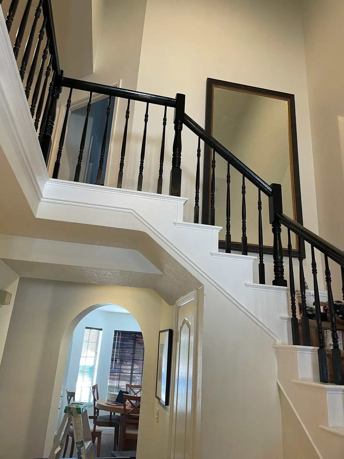 A staircase in a house with a black railing and a mirror on the wall.