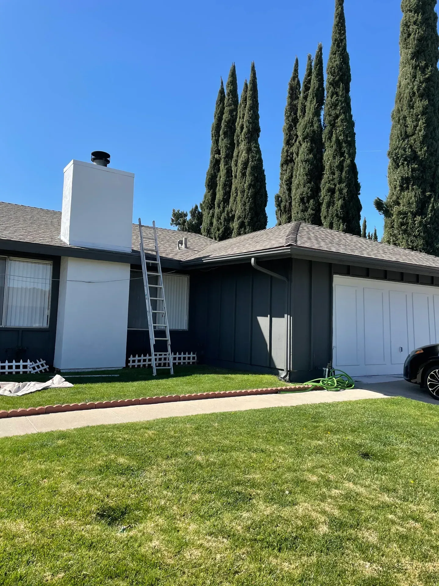 A house with a ladder in front of it and a car parked in front of it.