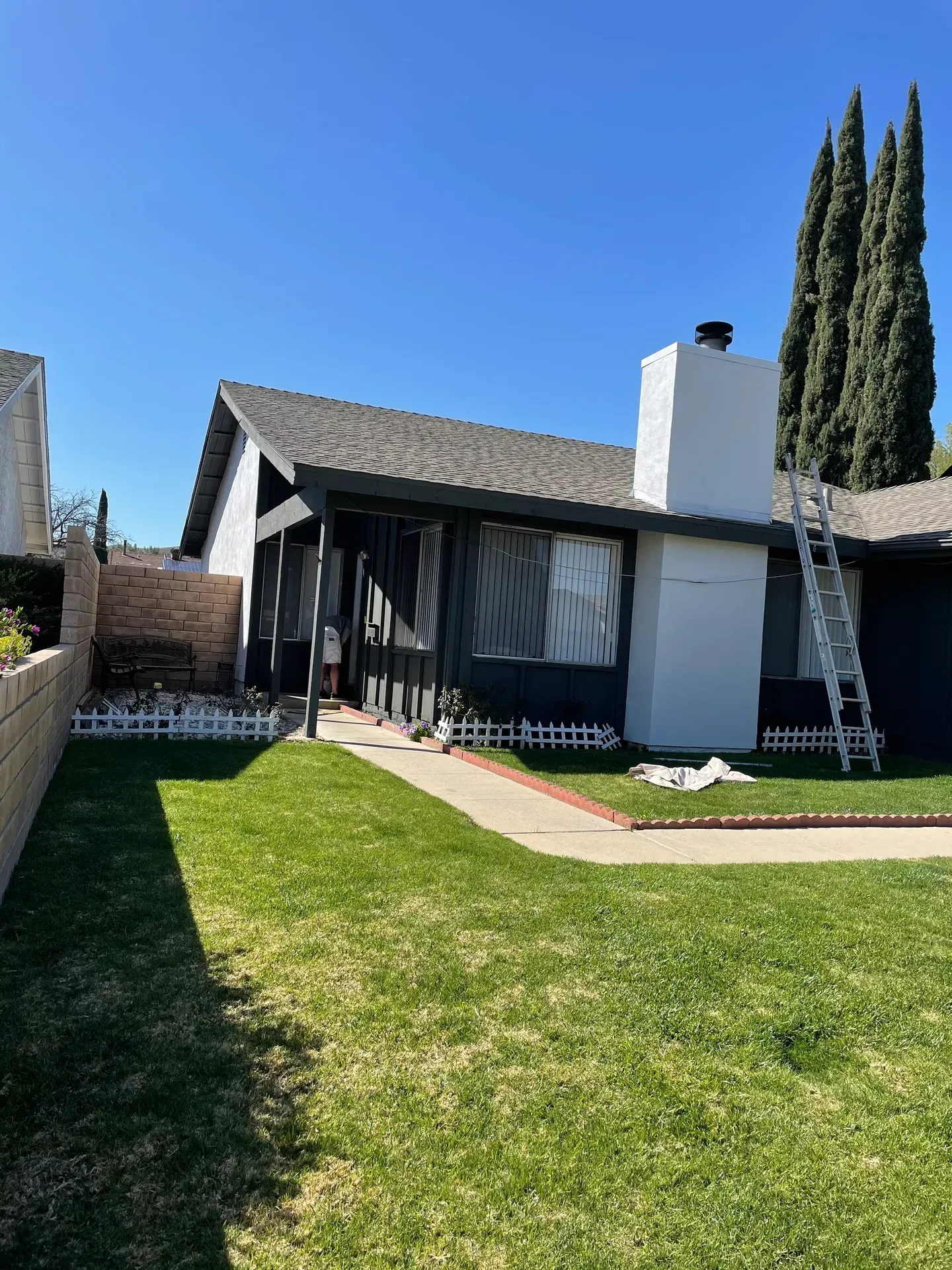 A house with a ladder in front of it is being painted.
