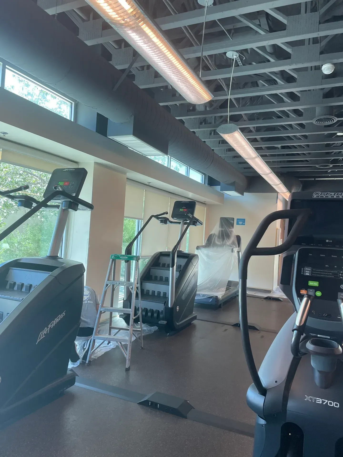 A gym with a lot of exercise equipment and a ladder