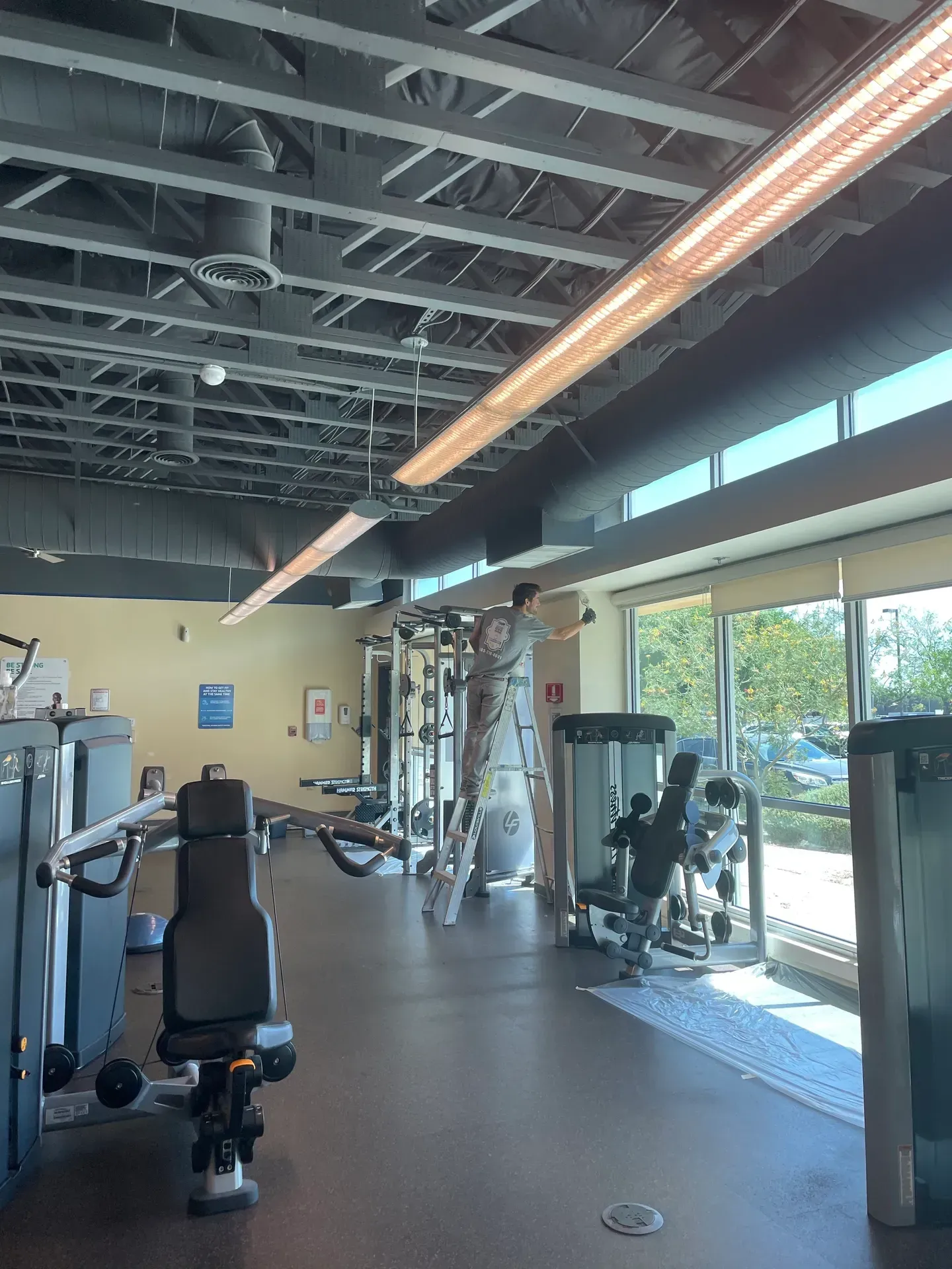 A man is standing on a ladder in a gym.