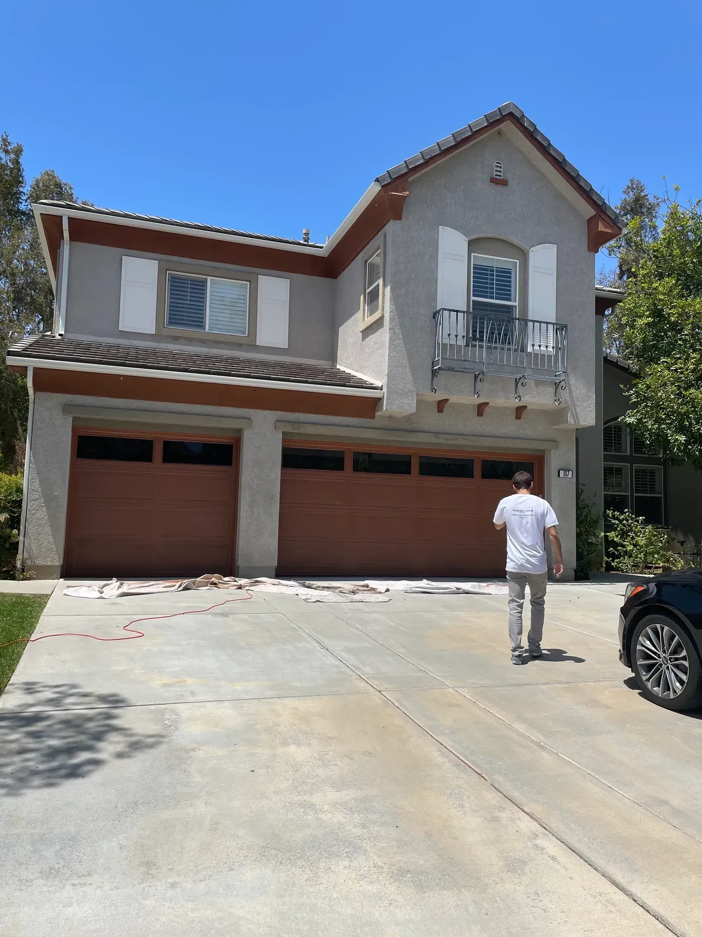 A man is walking down a driveway in front of a large house.