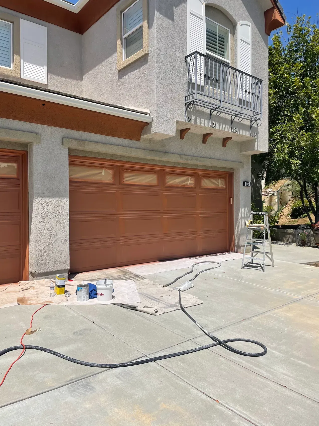 A garage door is being painted in front of a house.