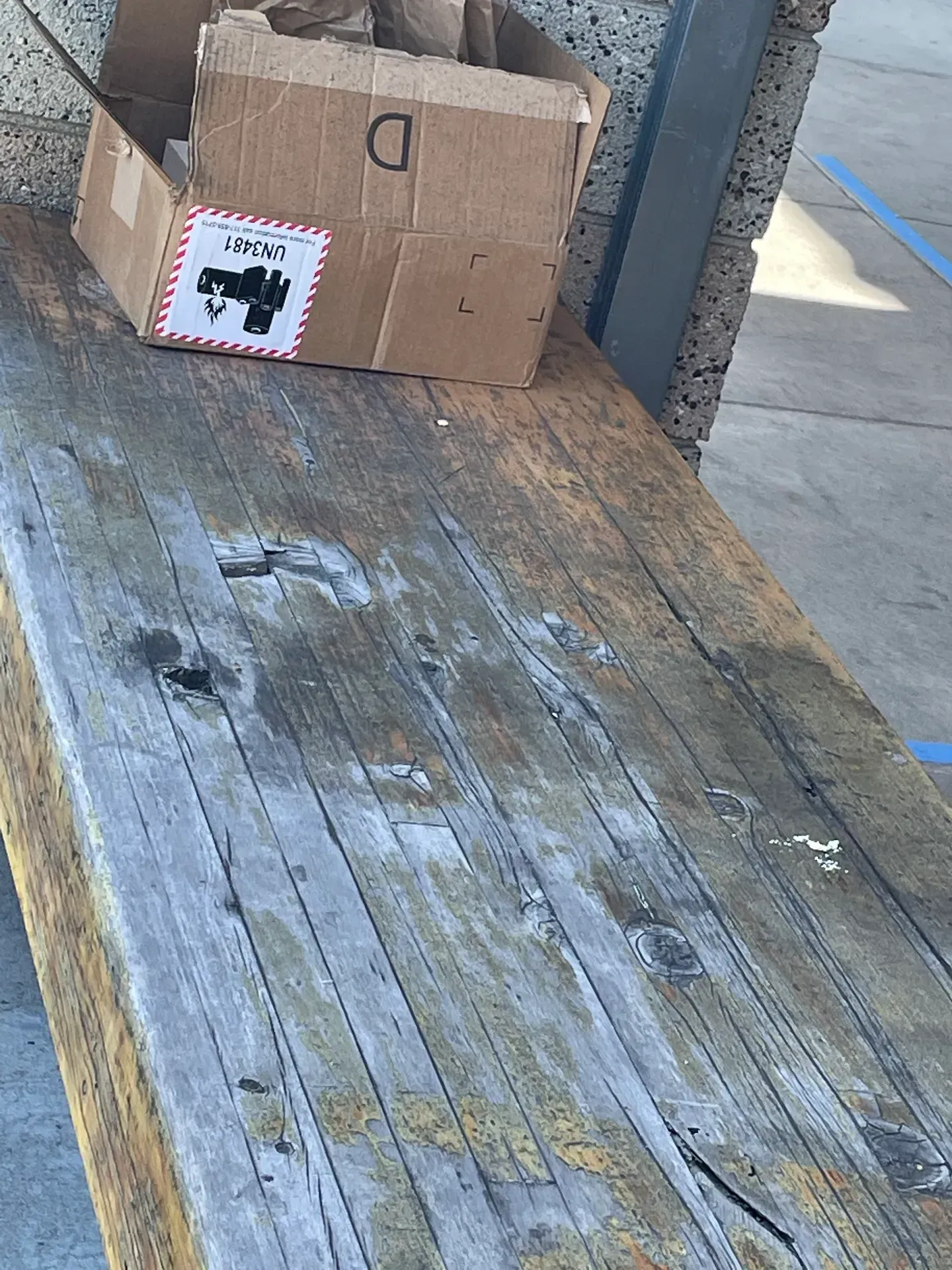 A cardboard box with the letter d on it sits on a wooden bench