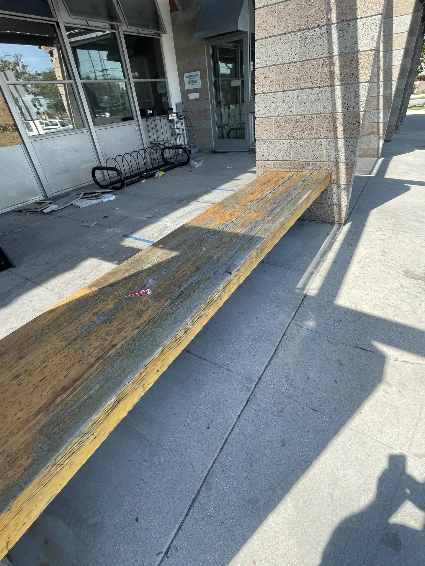 A wooden bench is sitting on the sidewalk in front of a building.