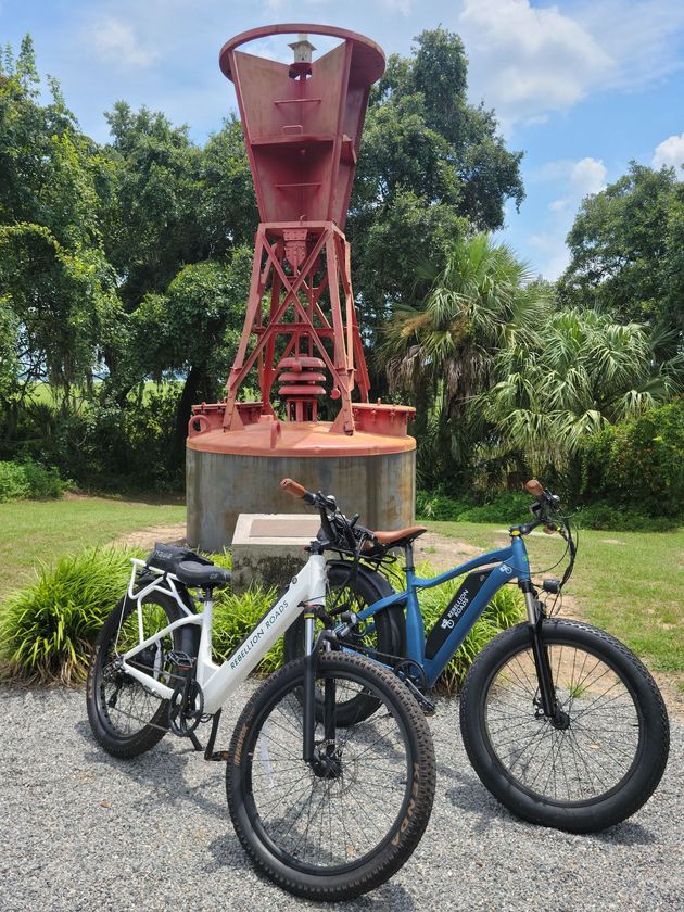 two electric bikes are parked next to each other in front of a statue .