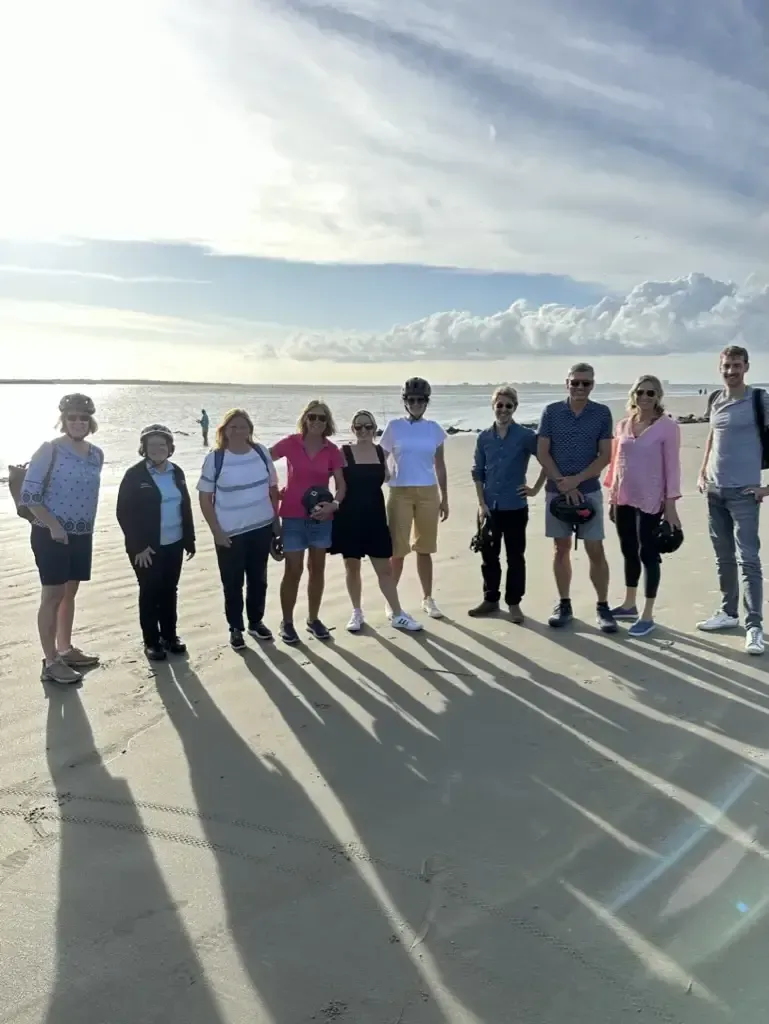 A group of people are standing on a beach on the Shores Tour