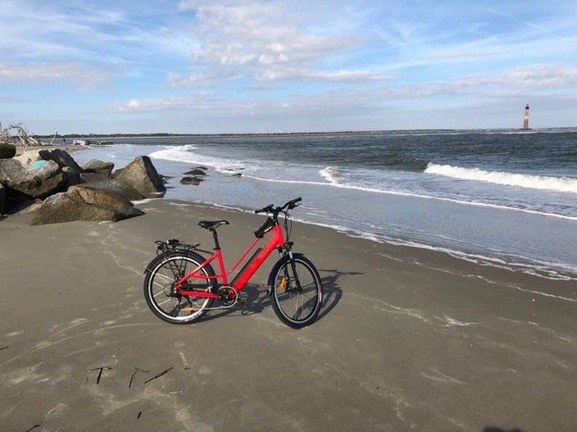 a red bicycle is parked on the beach near the ocean .
