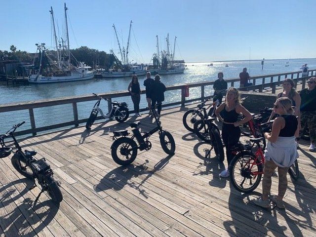 a group of people are standing on a pier with bikes parked on it .