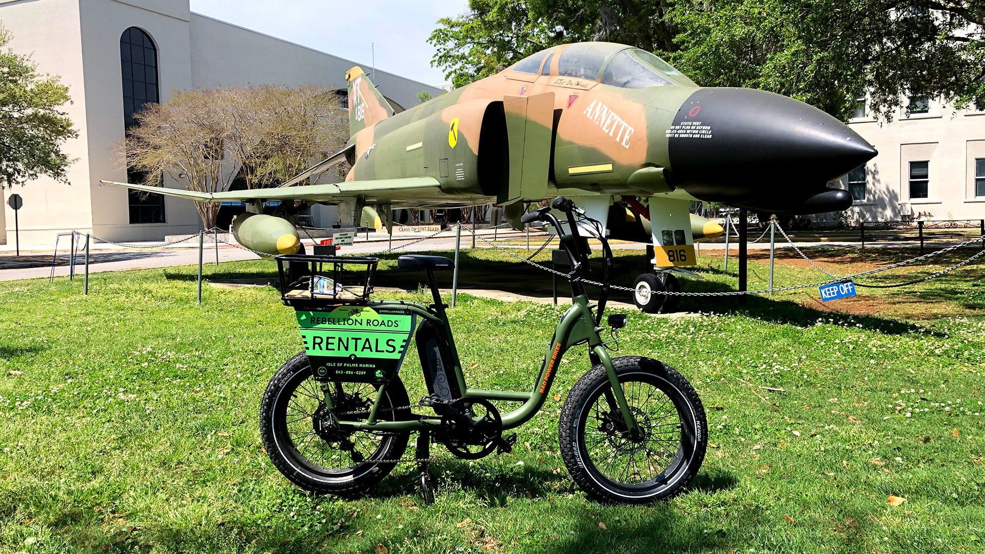 an electric bicycle is parked in front of a fighter jet .
