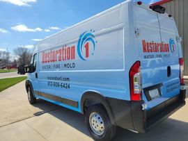 A restoration 1 van is parked on the side of the road.