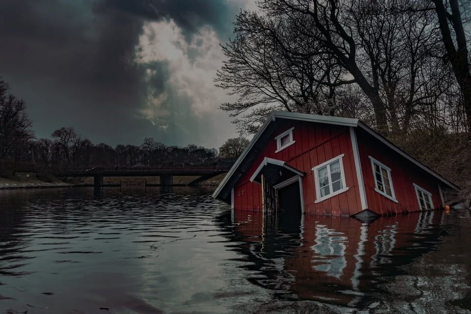 A red house is floating in the middle of a lake.