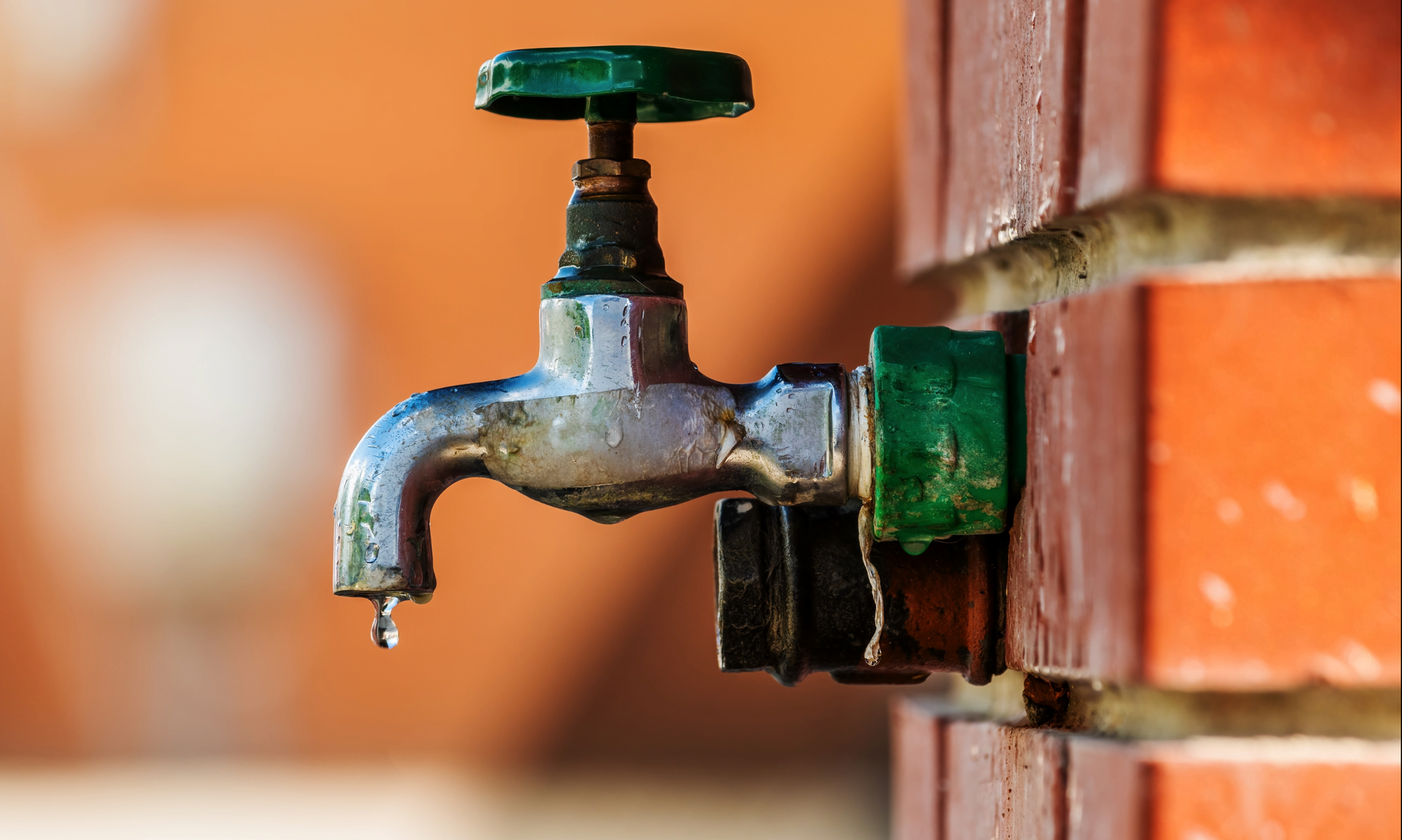 A close up of a water faucet on a brick wall.