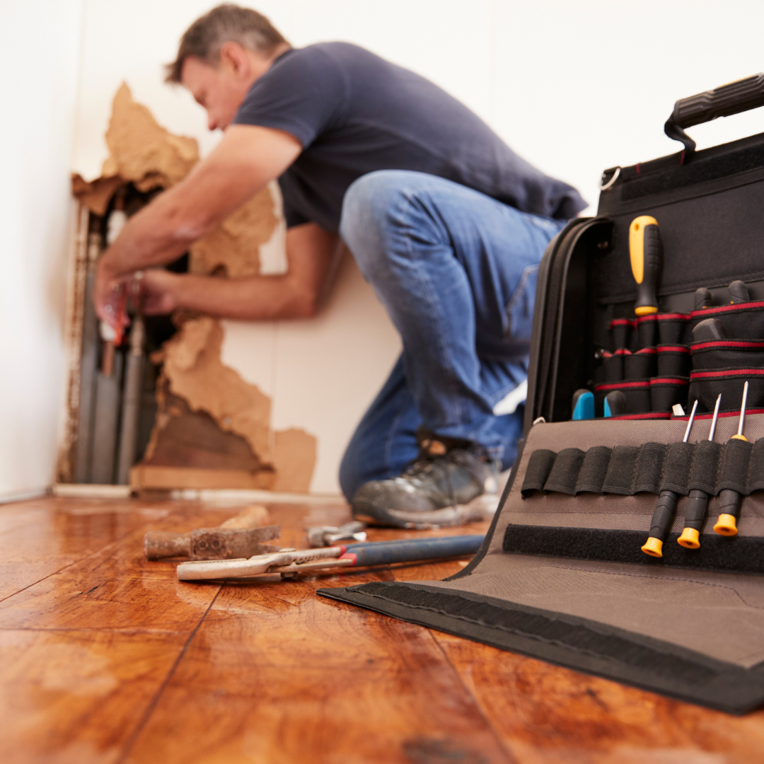 A man is working on a wall next to a tool bag.