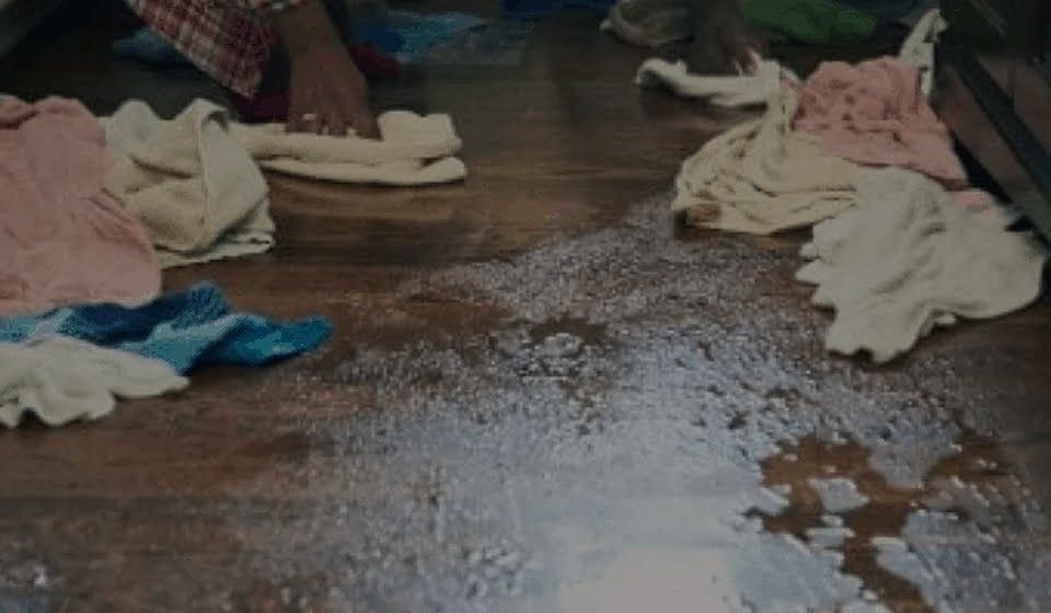 A person is cleaning a dirty floor with a mop.