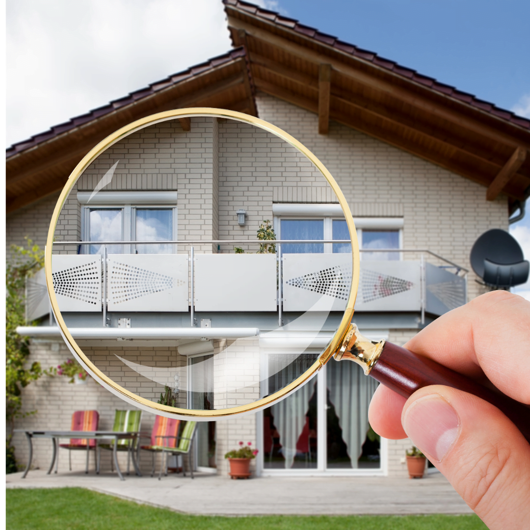 A person is holding a magnifying glass in front of a house.