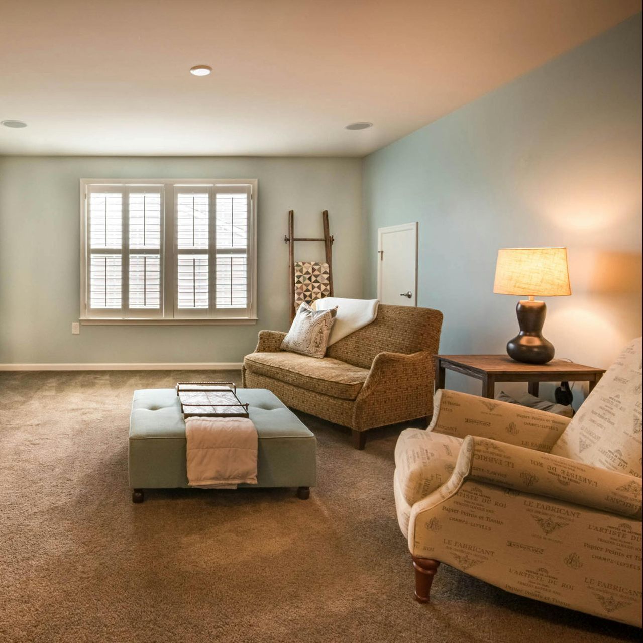 A living room with a couch chair and ottoman