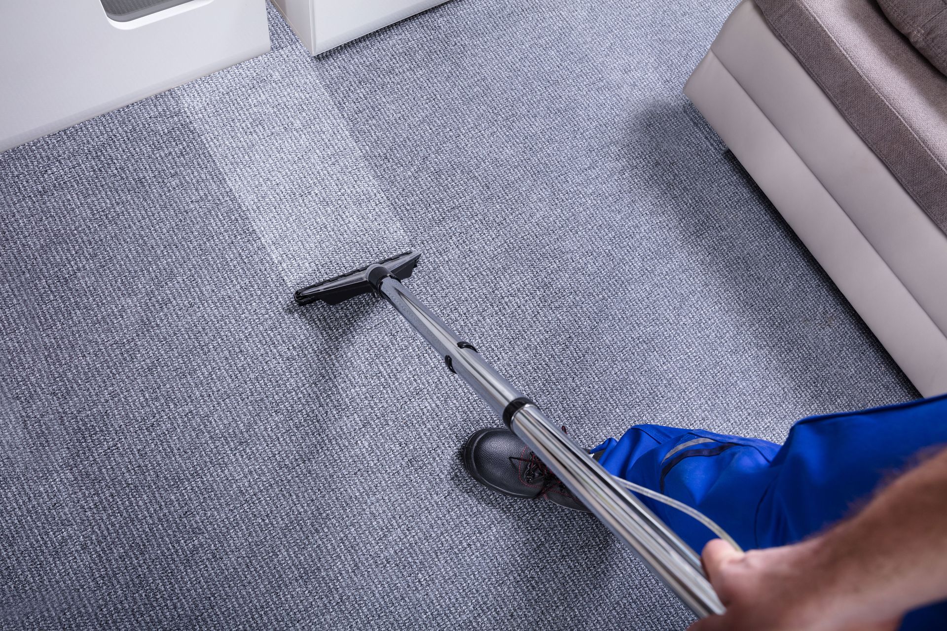 A person is using a vacuum cleaner to clean a carpet in a living room.