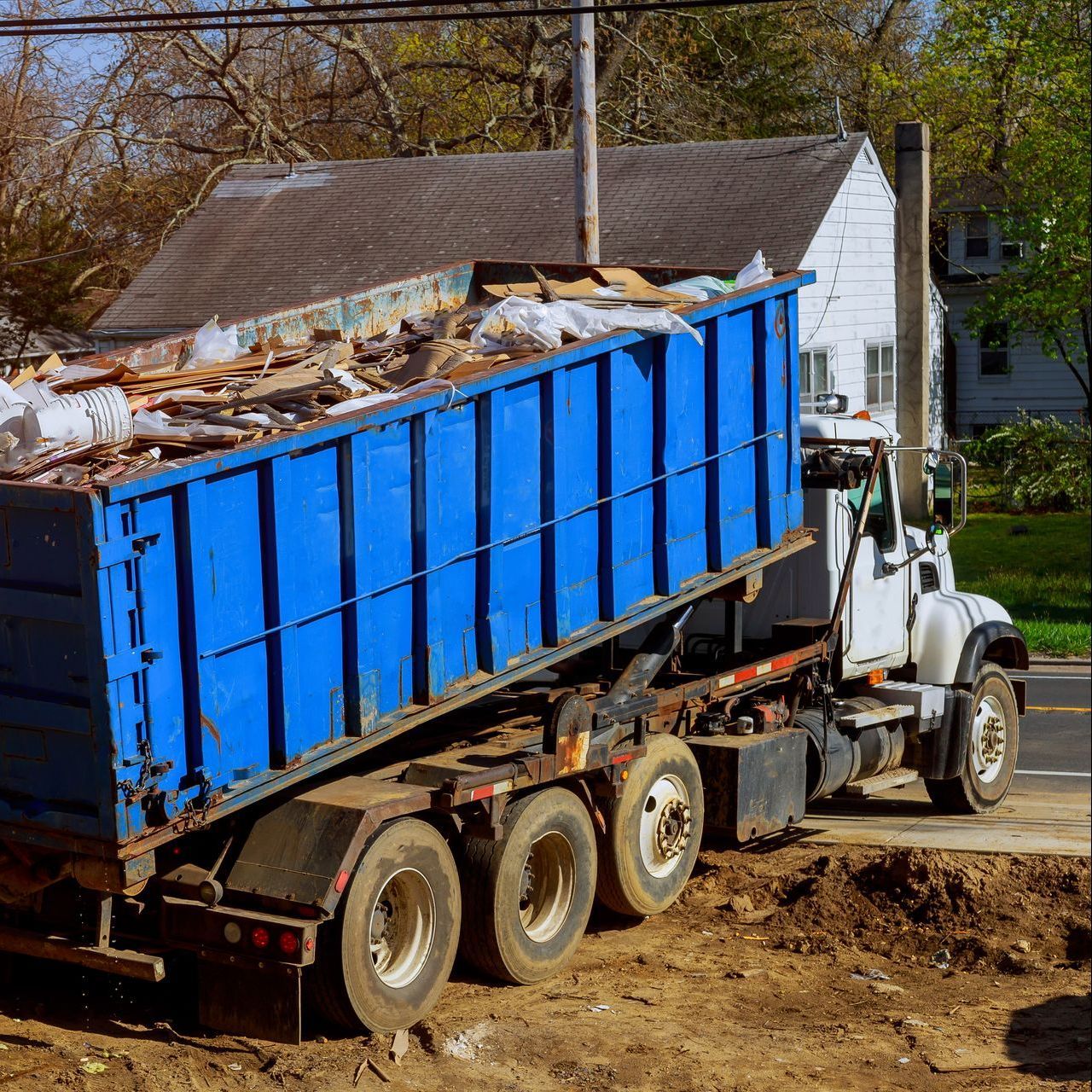 A blue dumpster truck is parked on the side of the road