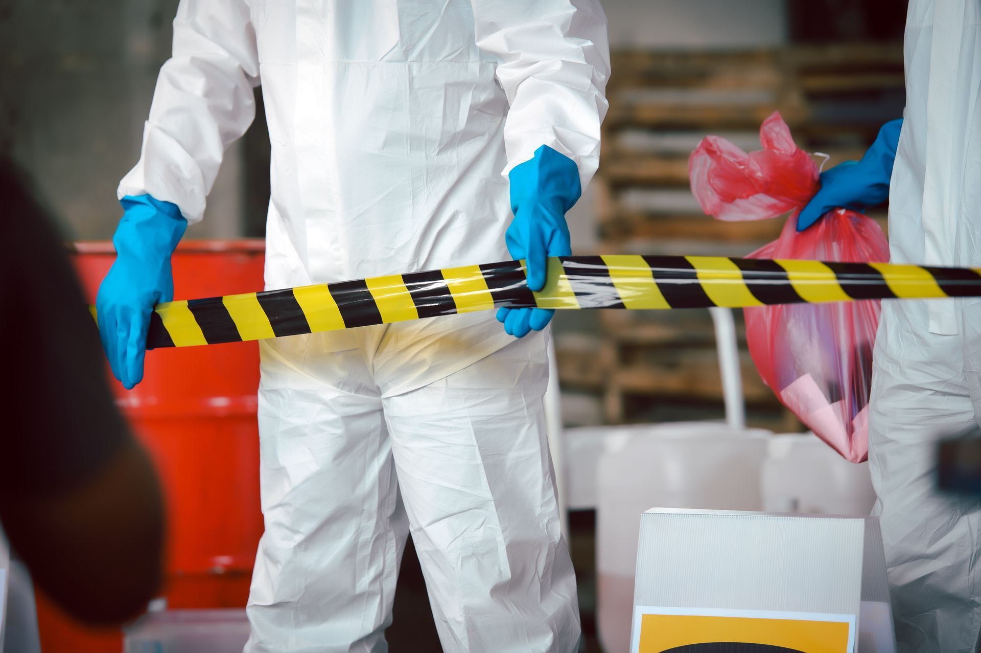 A man in a protective suit is holding a yellow and black tape.