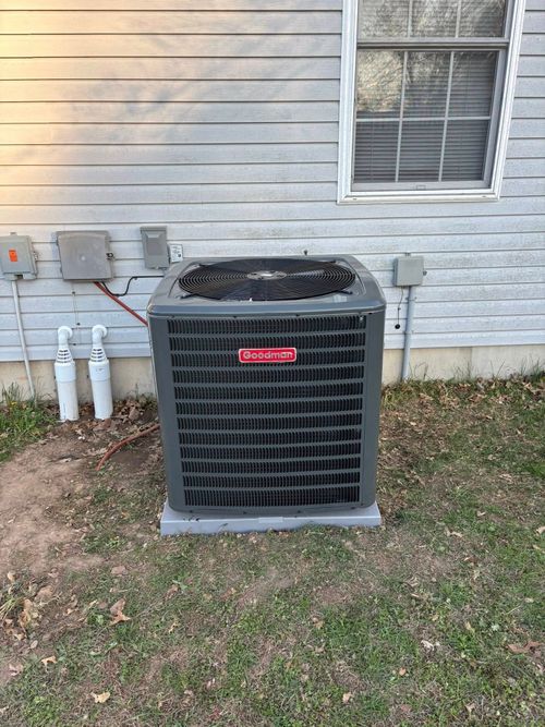 Gray Goodman air conditioning unit outside a house.