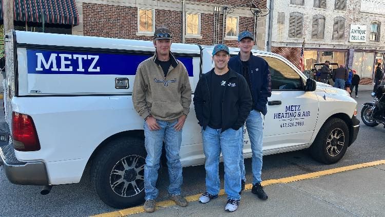 Three people stand beside a white truck with 