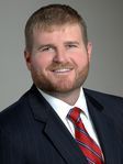 A man with a beard is wearing a suit and tie and smiling.