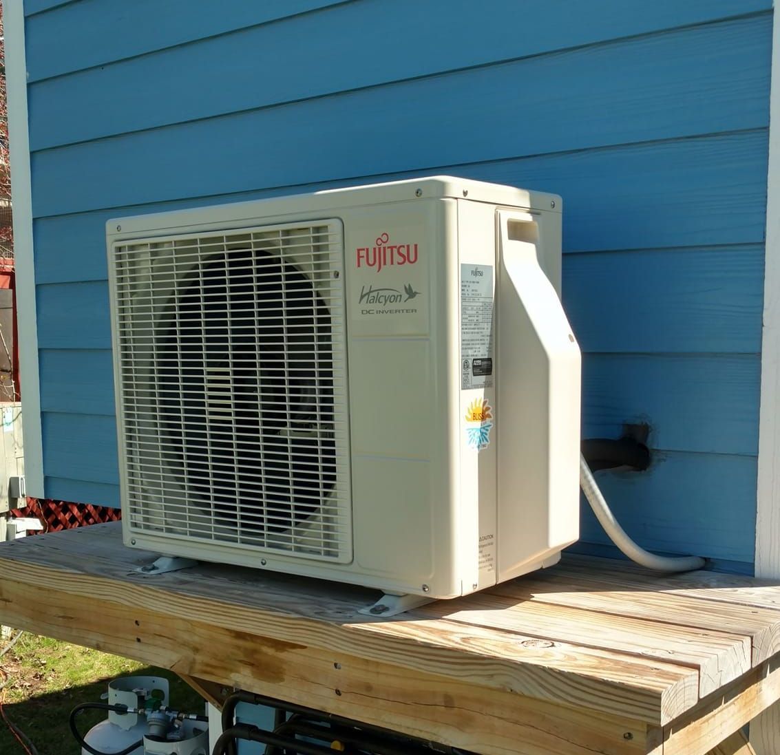 A fujitsu air conditioner is sitting on a wooden deck