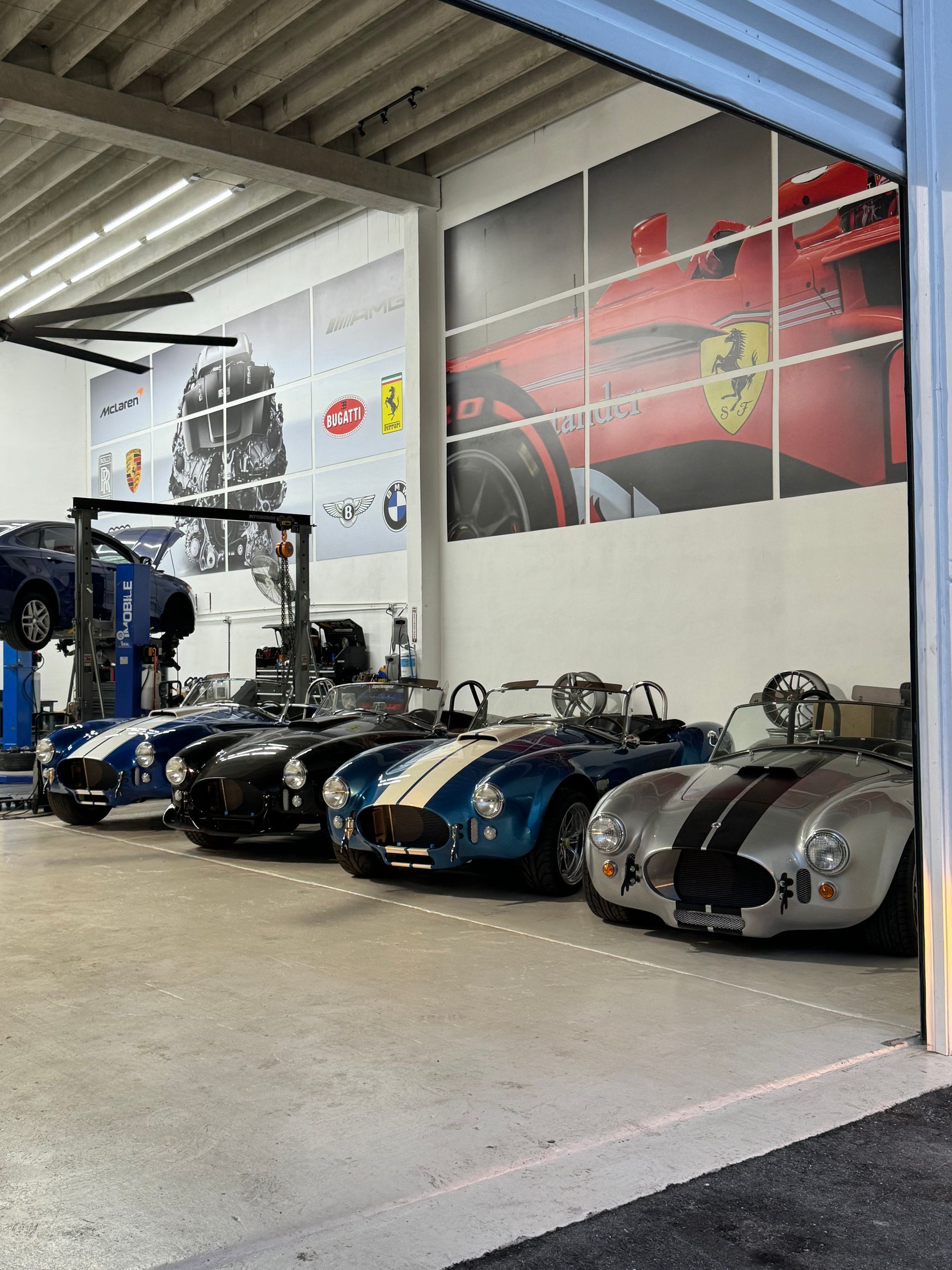 A row of sports cars are parked in a garage.