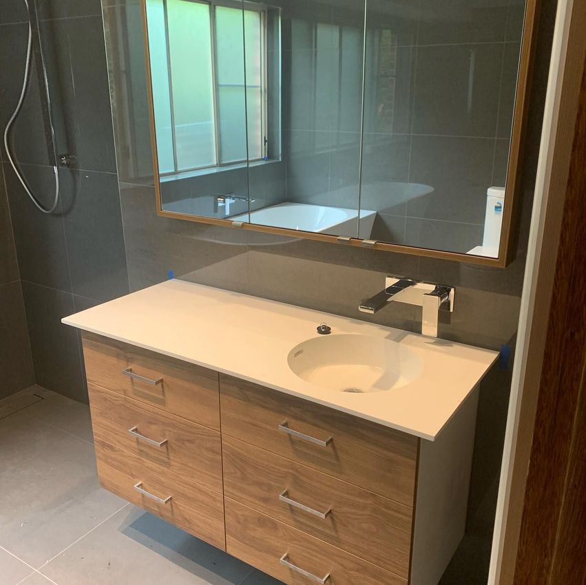 Sink with wooden cabinet and three mirrors — Plumbers in Illawarra, NSW