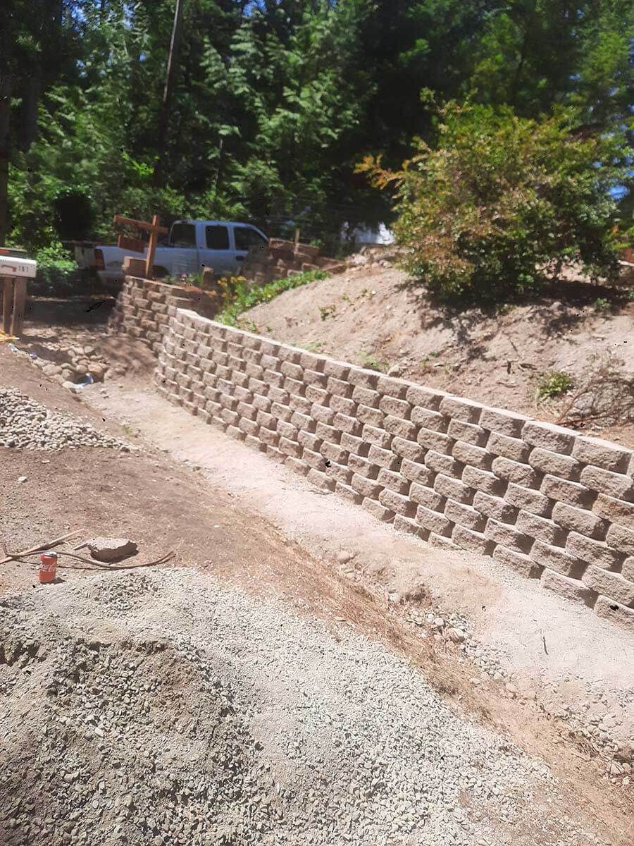 A brick wall is being built in the middle of a dirt road.