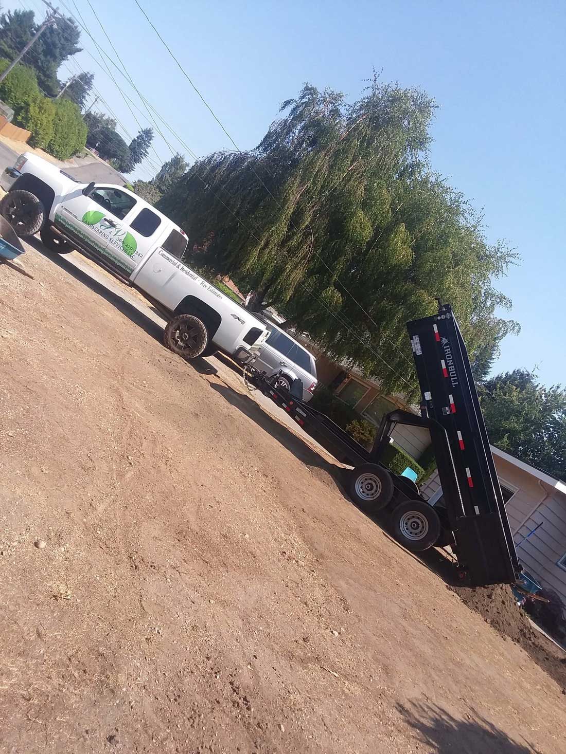 A truck with a trailer attached to it is parked on the side of the road.