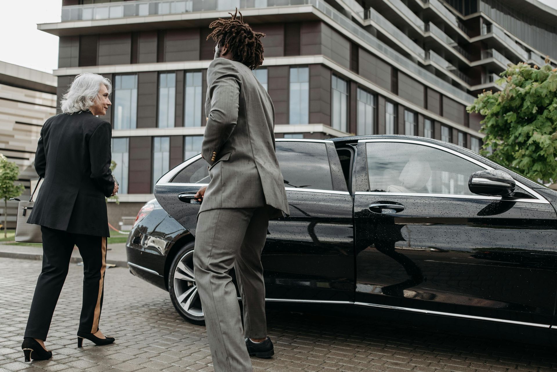 A man and a woman are standing next to a black car.