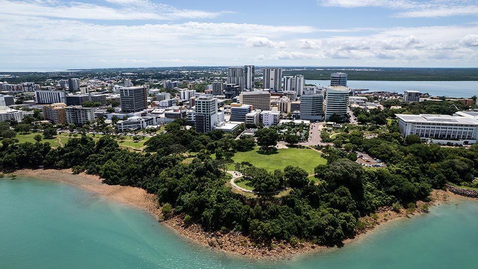 Woman with tattoos sits at a table with a laptop, smiling.