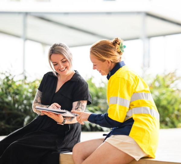 Man in blue suit speaking in a meeting. Other people seated around a table. Modern office setting.