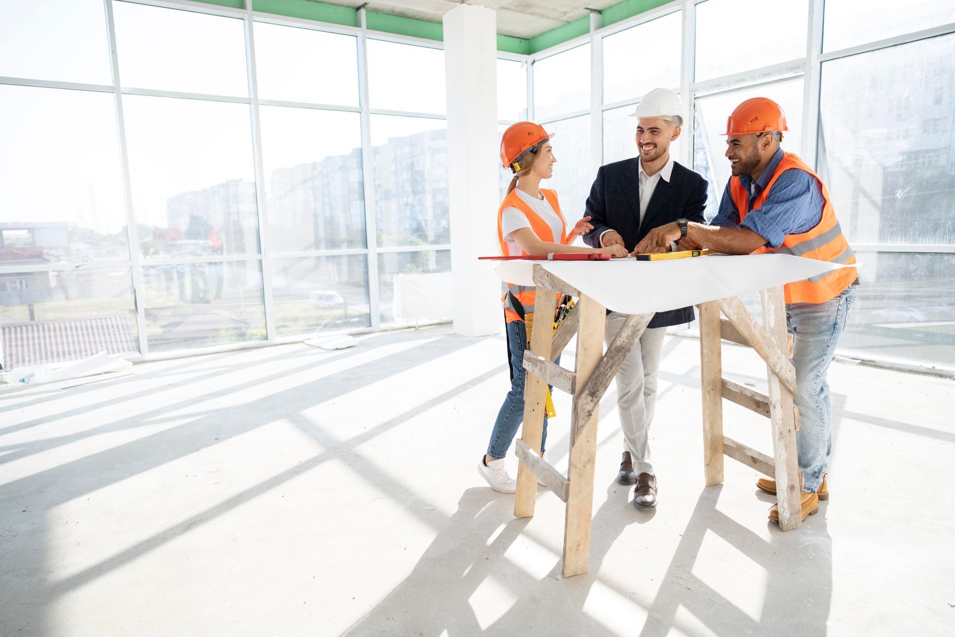 Construction workers and architect reviewing plans at a construction site, wearing hard hats and safety vests.