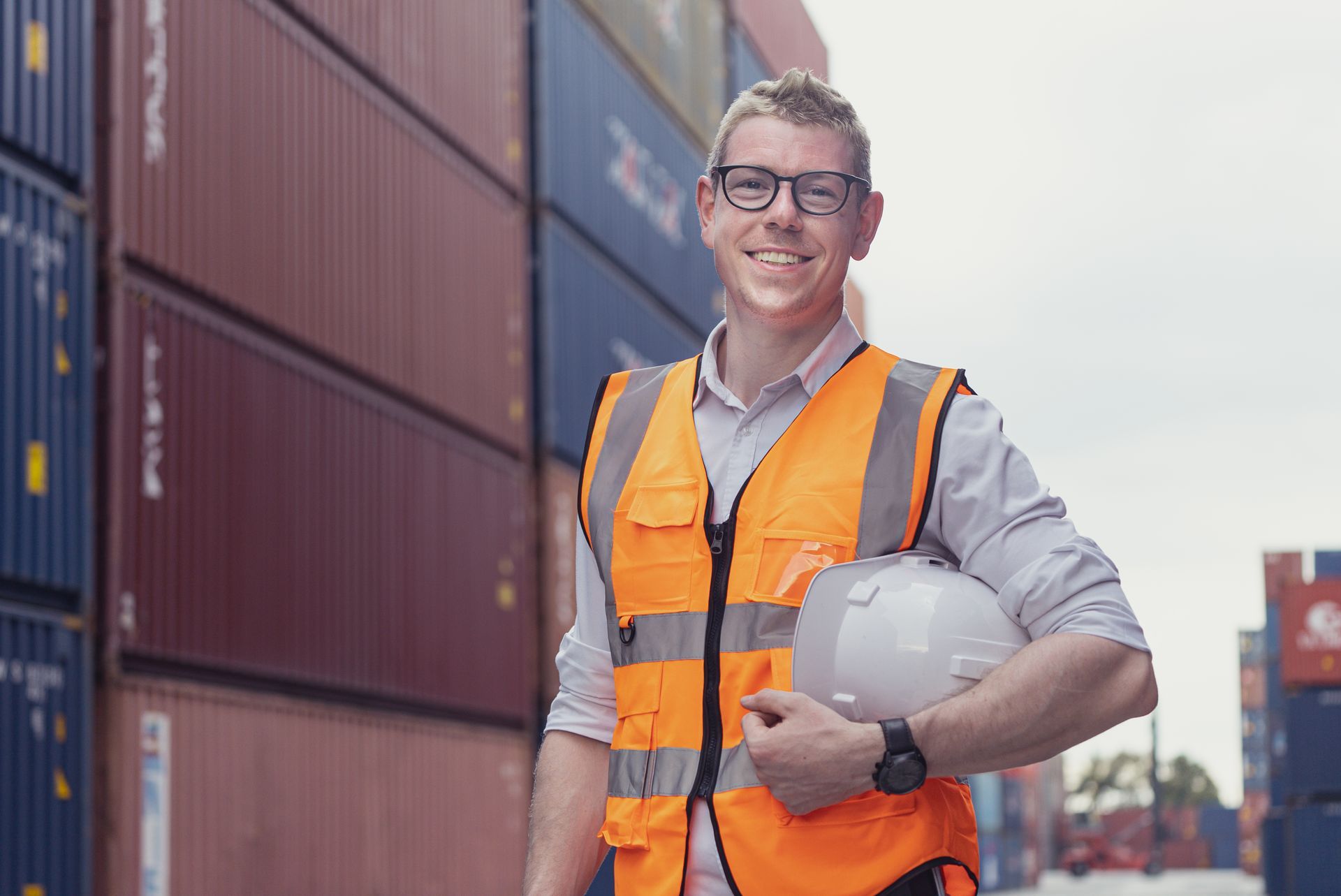 Man in blue suit speaking in a meeting. Other people seated around a table listen. Office setting.